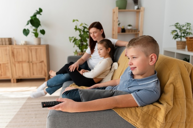 Mamá viendo la televisión con sus hijos.