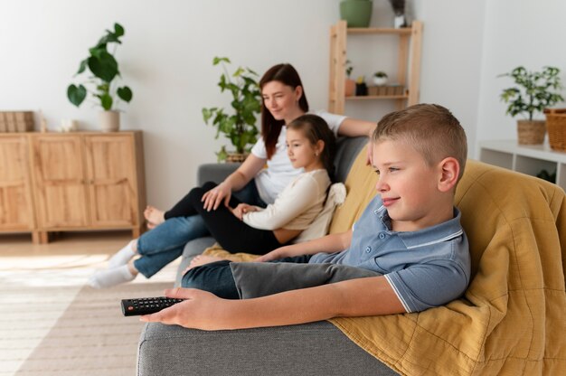 Mamá viendo la televisión con sus hijos.