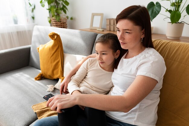 Mamá viendo la televisión con sus hijos.