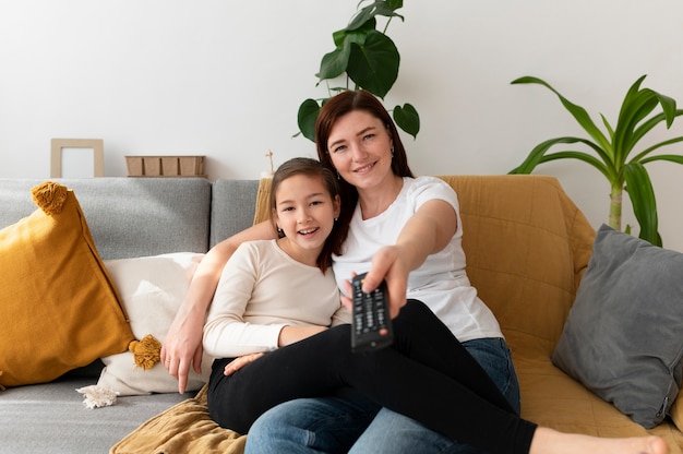 Mamá viendo la televisión con sus hijos.