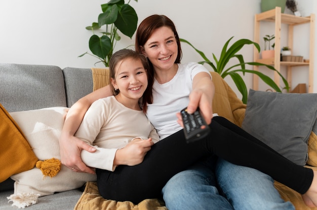 Mamá viendo la televisión con sus hijos.