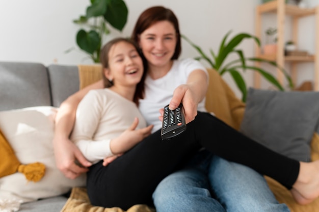 Mamá viendo la televisión con sus hijos.