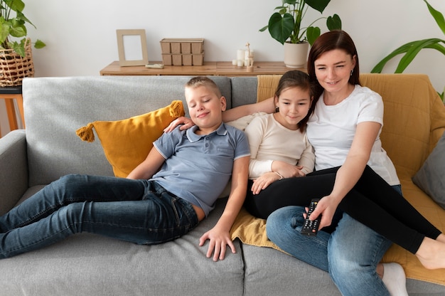 Mamá viendo la televisión con sus hijos.