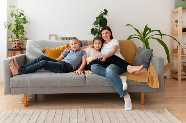 Mamá viendo la televisión con sus hijos.