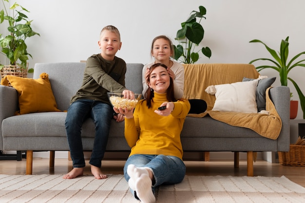 Mamá viendo la televisión con sus hijos.