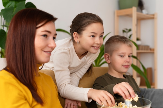 Mamá viendo la televisión con sus hijos.