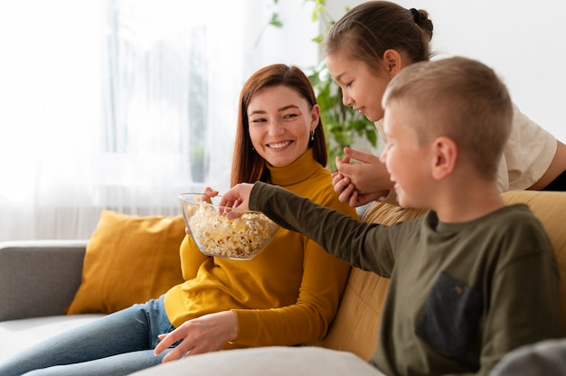 Foto gratuita mamá viendo la televisión con sus hijos.