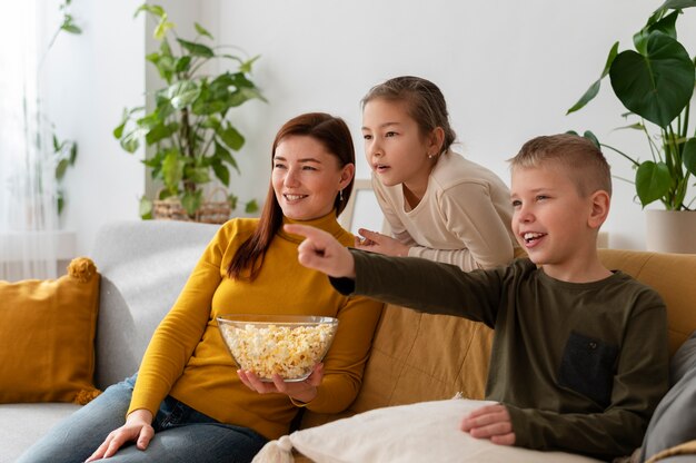 Mamá viendo la televisión con sus hijos.