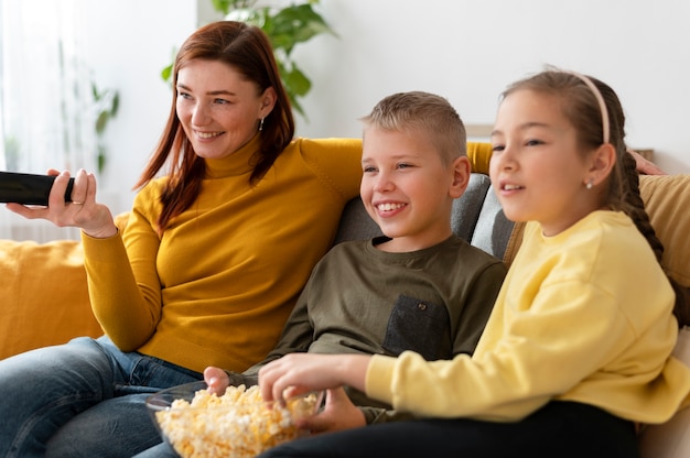 Mamá viendo la televisión con sus hijos.