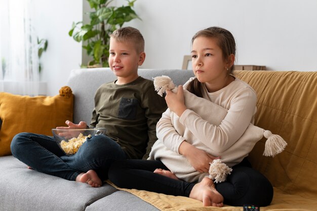 Mamá viendo la televisión con sus hijos.