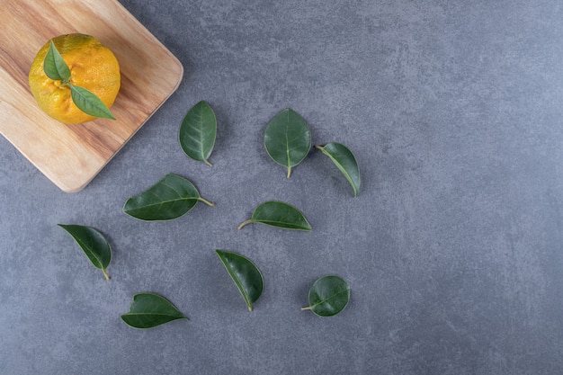 Mandarina fresca sobre tabla de madera y hojas.