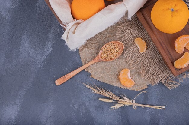 Mandarinas frescas en caja de madera y rodajas de mandarinas sobre arpillera.