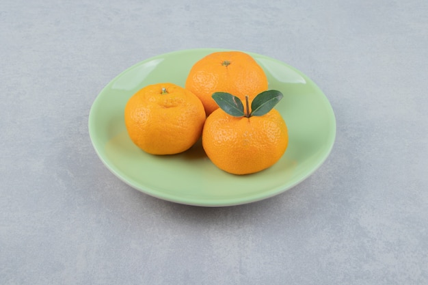 Mandarinas frescas con hojas en placa verde