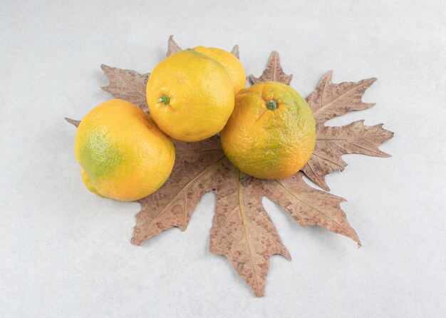 Mandarinas frescas con hojas secas en el cuadro blanco.