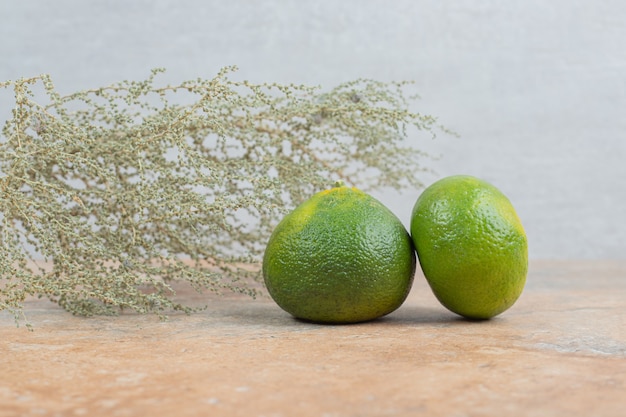 Mandarinas frescas sobre fondo de mármol con hierba.