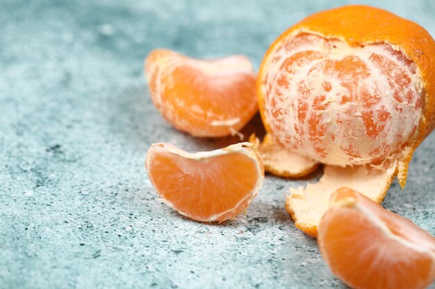 Mandarinas peladas y en rodajas sobre un fondo azul.