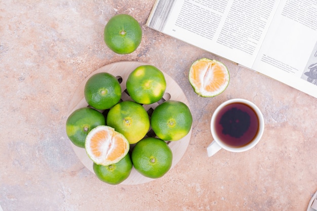 Mandarinas verdes con una taza de té.