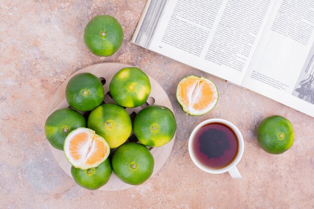 Mandarinas verdes con una taza de té