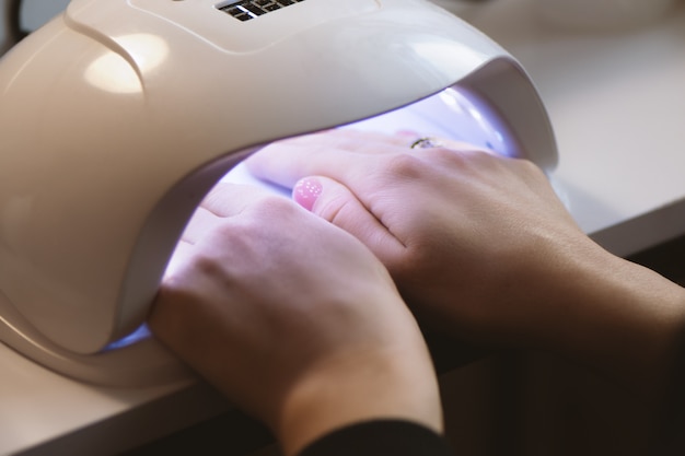 Manicurista haciendo gel diseño de uñas para el cliente, de cerca.