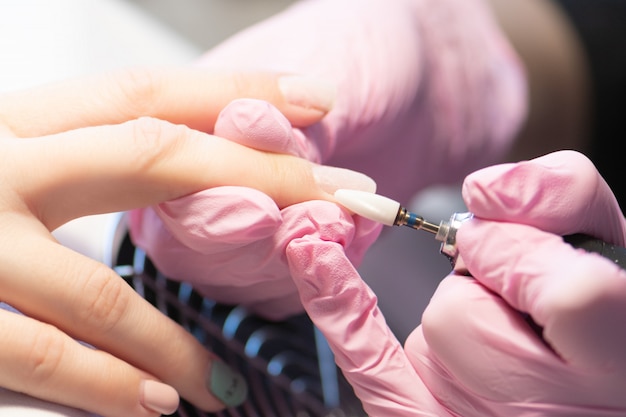 Manicurista haciendo gel diseño de uñas para el cliente, de cerca.