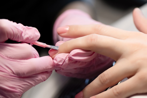 Manicurista haciendo gel diseño de uñas para el cliente, de cerca.