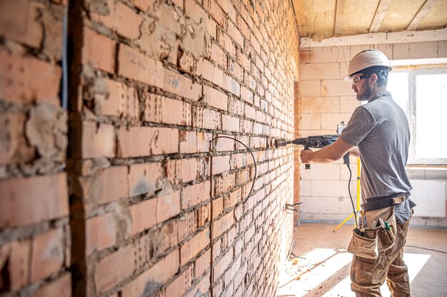 Manitas en un sitio de construcción en el proceso de perforación de una pared con un perforador