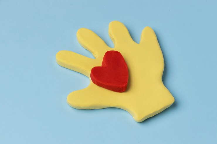 Foto gratuito mano de alto ángulo con corazón rojo de plastilina