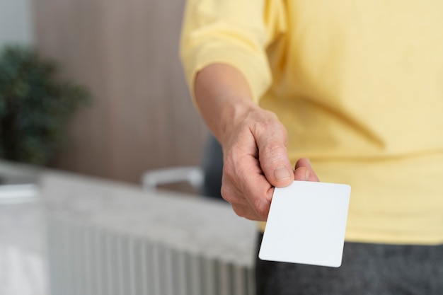 Mano de alto ángulo que sostiene la tarjeta de visita en blanco