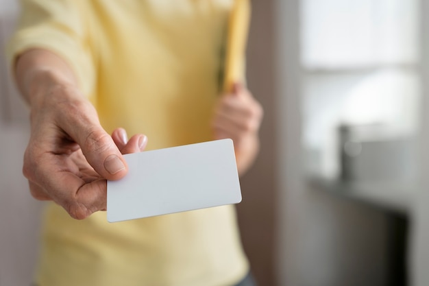 Mano de alto ángulo que sostiene la tarjeta de visita en blanco