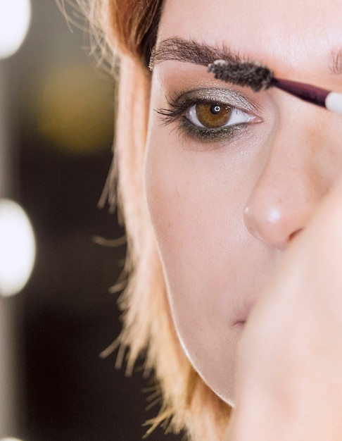 Mano aplicando gel de cejas en mujer