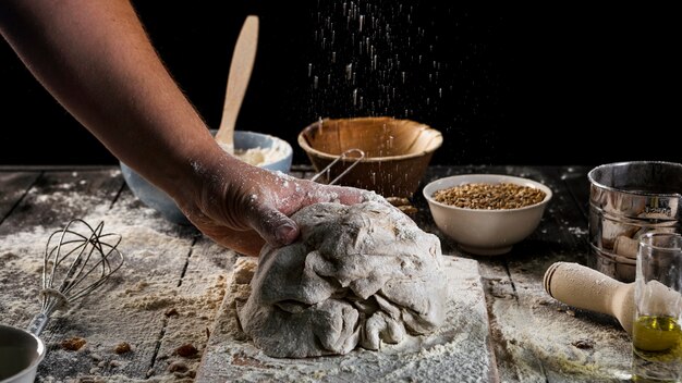 Mano de Baker amasando la masa en la mesa de la hornada