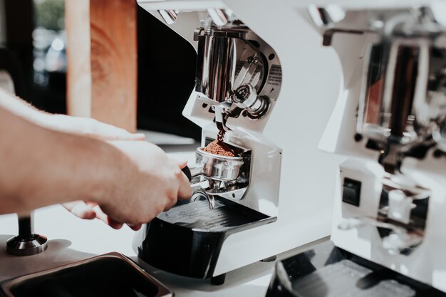 Mano de un barista haciendo café con una máquina de café en un café.