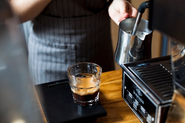 Mano de barista humeante leche para hacer café con leche en cafés