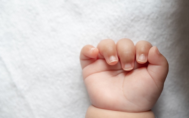 Mano de bebé recién nacido en la cama blanca