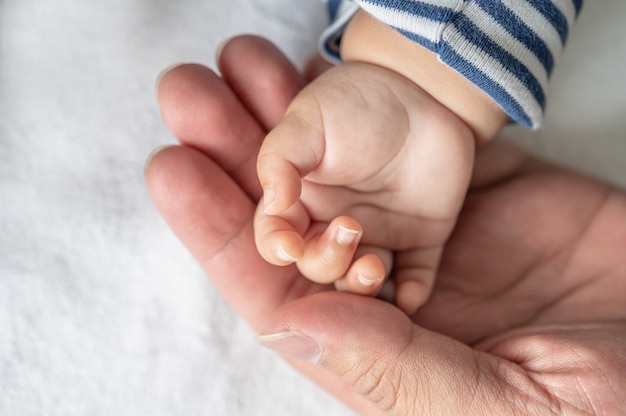 Mano de bebé recién nacido en la cama blanca