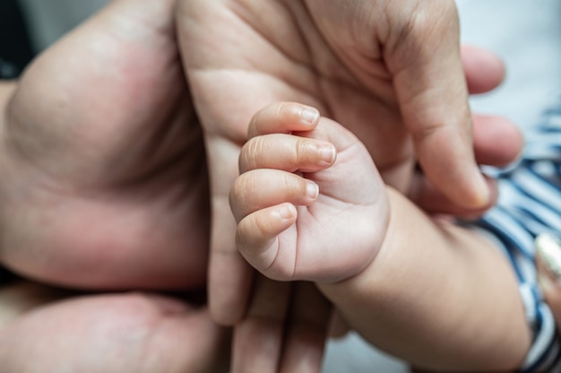 Mano de bebé recién nacido en la cama blanca