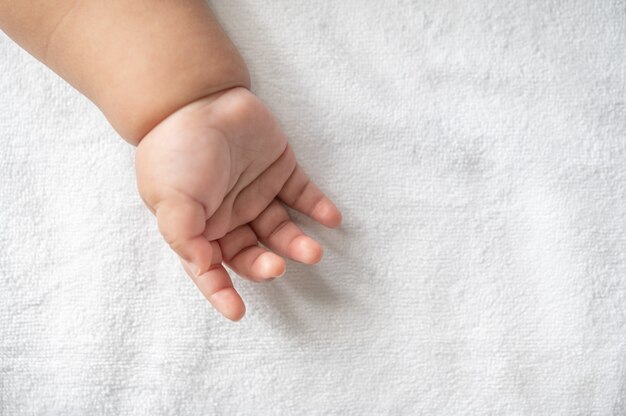 Mano de bebé recién nacido en la cama blanca