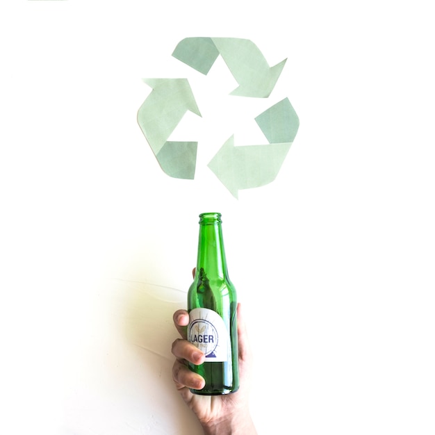 Mano con botella cerca de reciclar símbolo