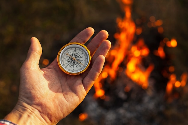 Mano con brújula y llamas de fuego a lo largo