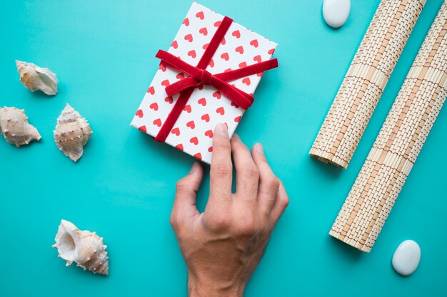 Mano con caja de regalos y elementos decorativos