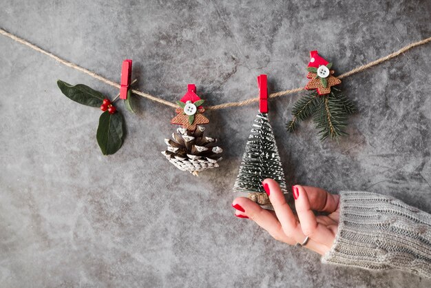 Mano cerca de decoraciones navideñas colgando de hilo