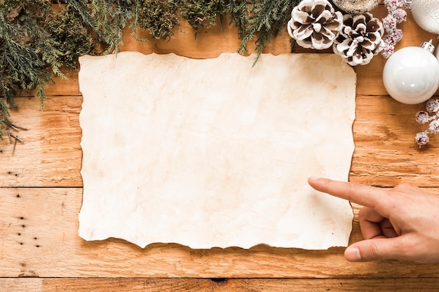 Mano cerca de papel entre adornos navideños.