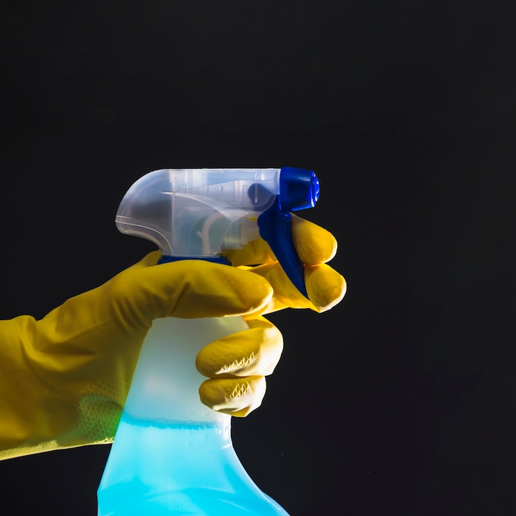 Foto gratuito mano del conserje con guantes amarillos sosteniendo la botella del aerosol