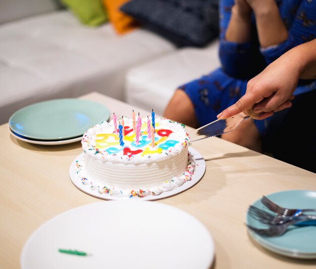 Mano cortando pastel de cumpleaños