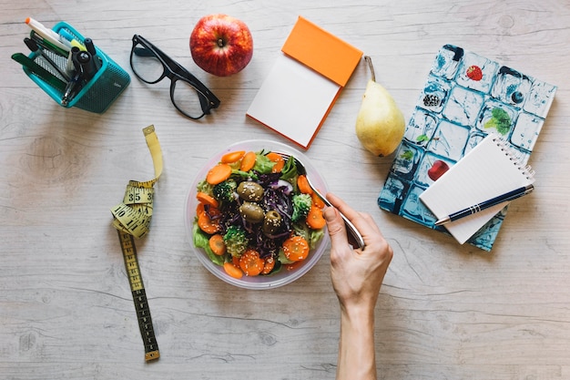 Foto gratuita mano de cosecha mezcla de ensalada en la oficina