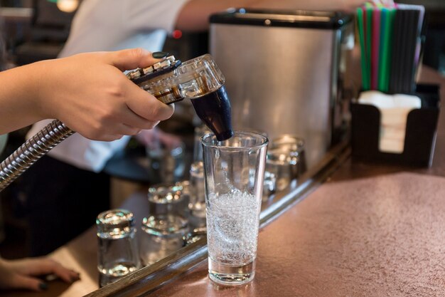 Mano de cosecha verter refresco en vidrio