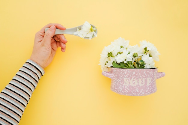 Mano de cultivo cerca de una olla con flores