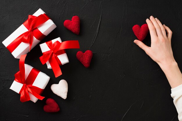 Mano de cultivo tocando el corazón cerca de regalos