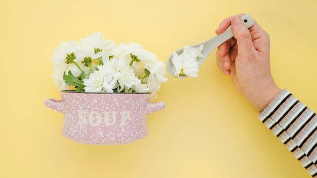 Mano de cultivo tomando flores de una olla