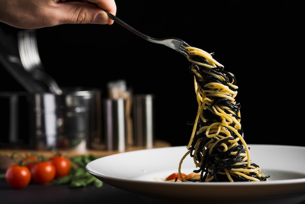 Mano de cultivo tomando pasta del plato